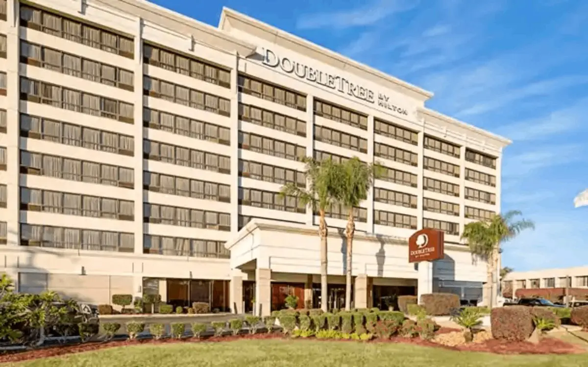 Hotel exterior with palm trees and sign.