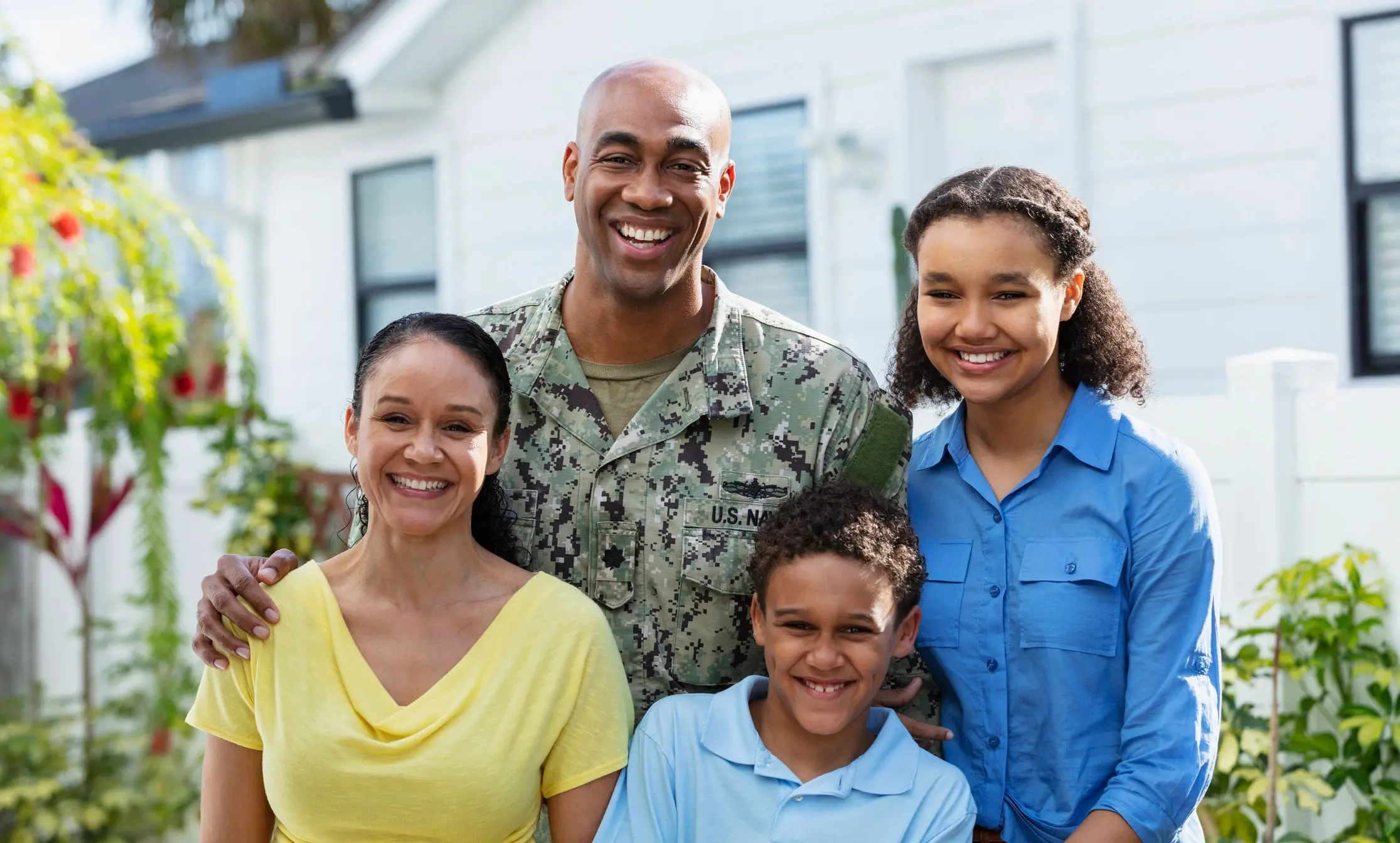 Smiling family with military member outdoors.