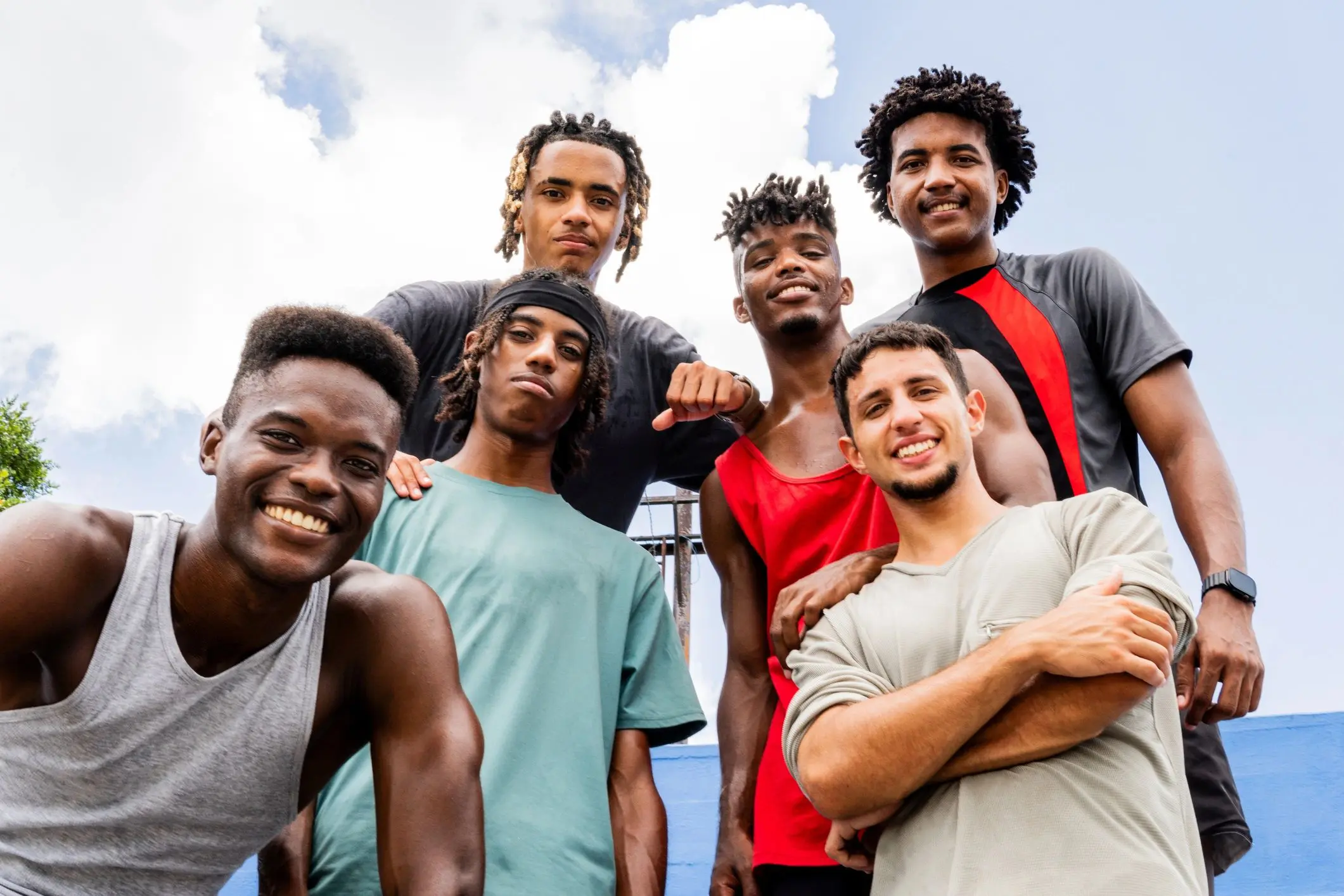 Group of smiling friends outdoors under blue sky.