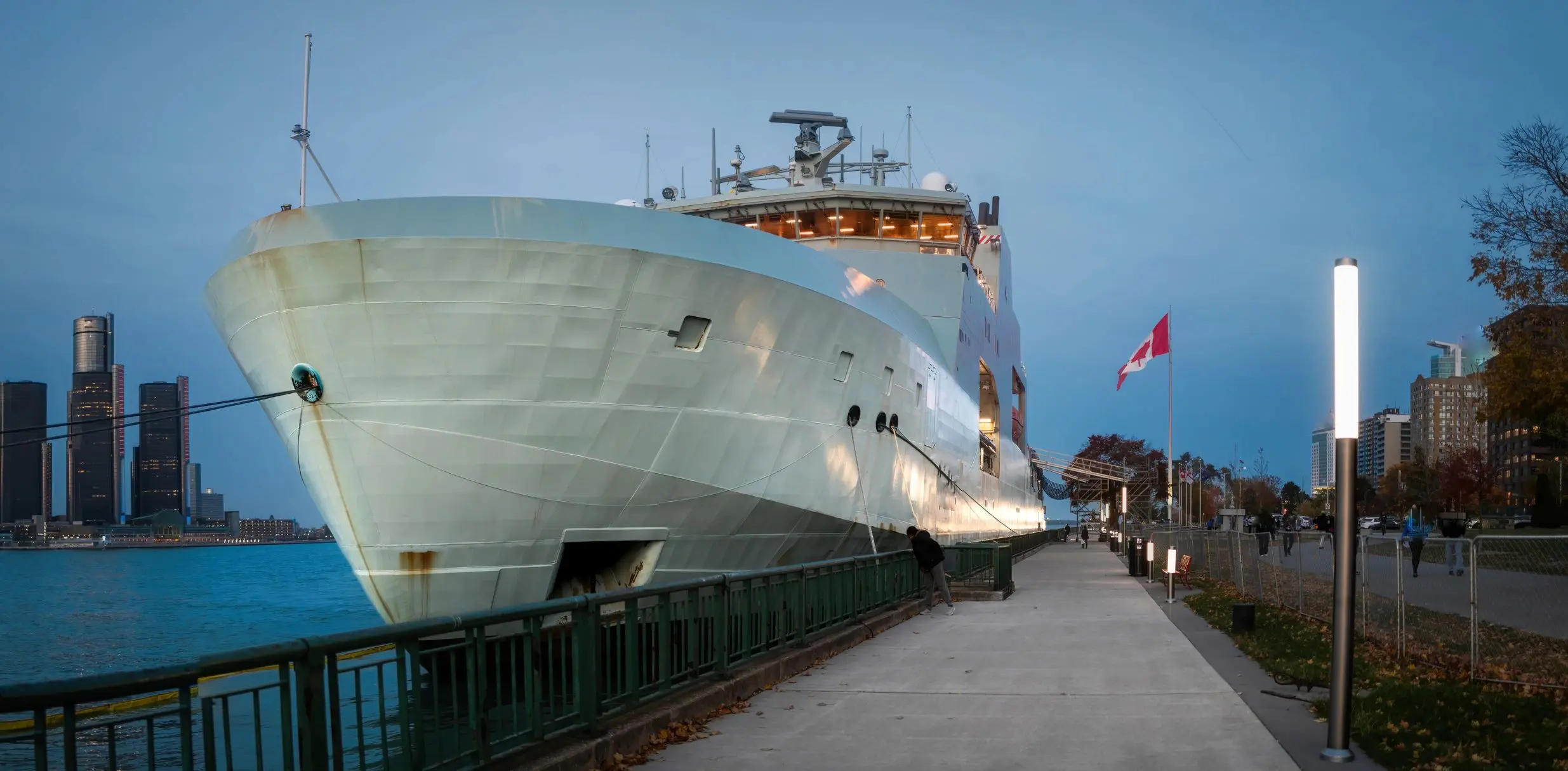 Large ship docked beside city walkway.