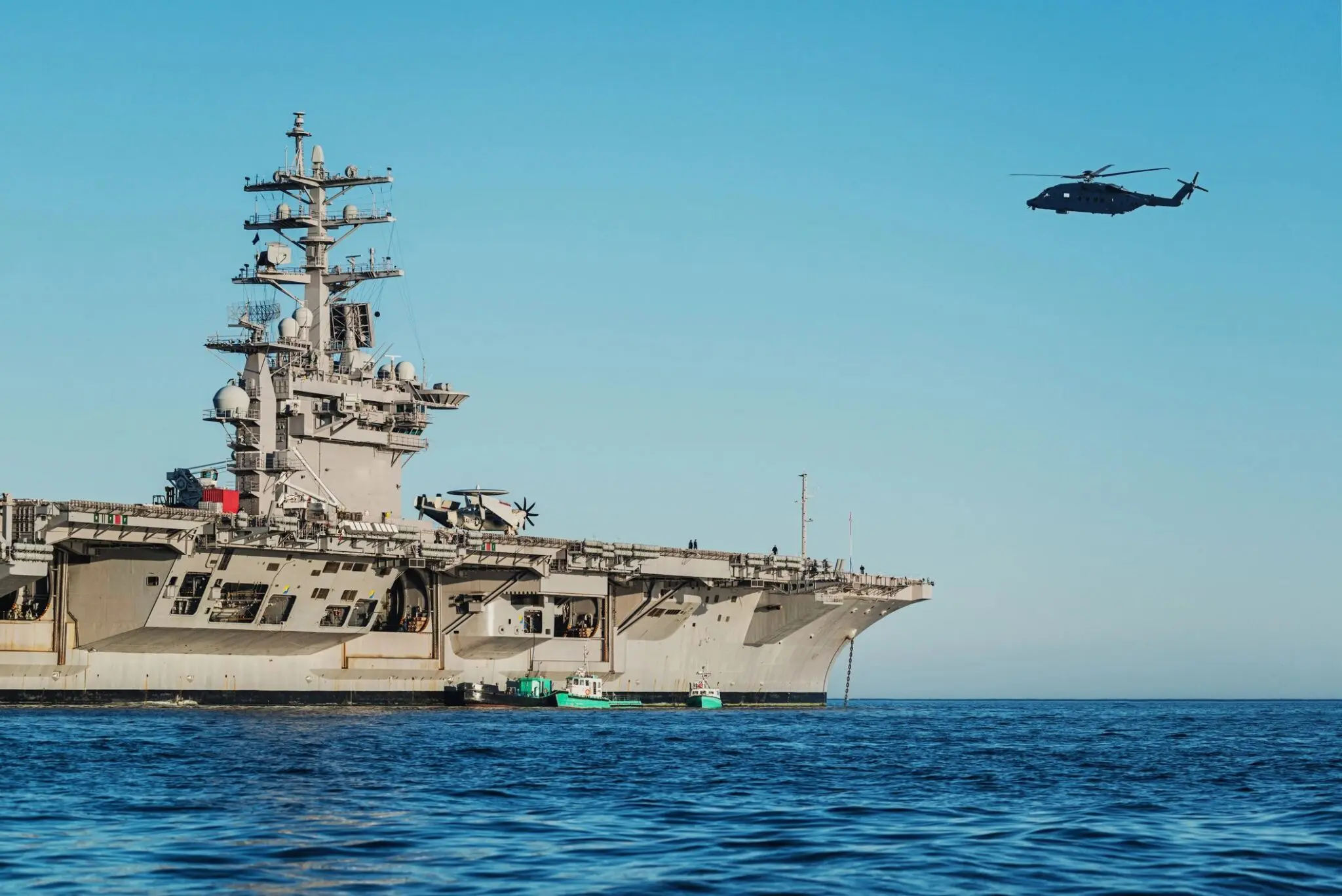 Aircraft carrier with helicopter flying nearby.