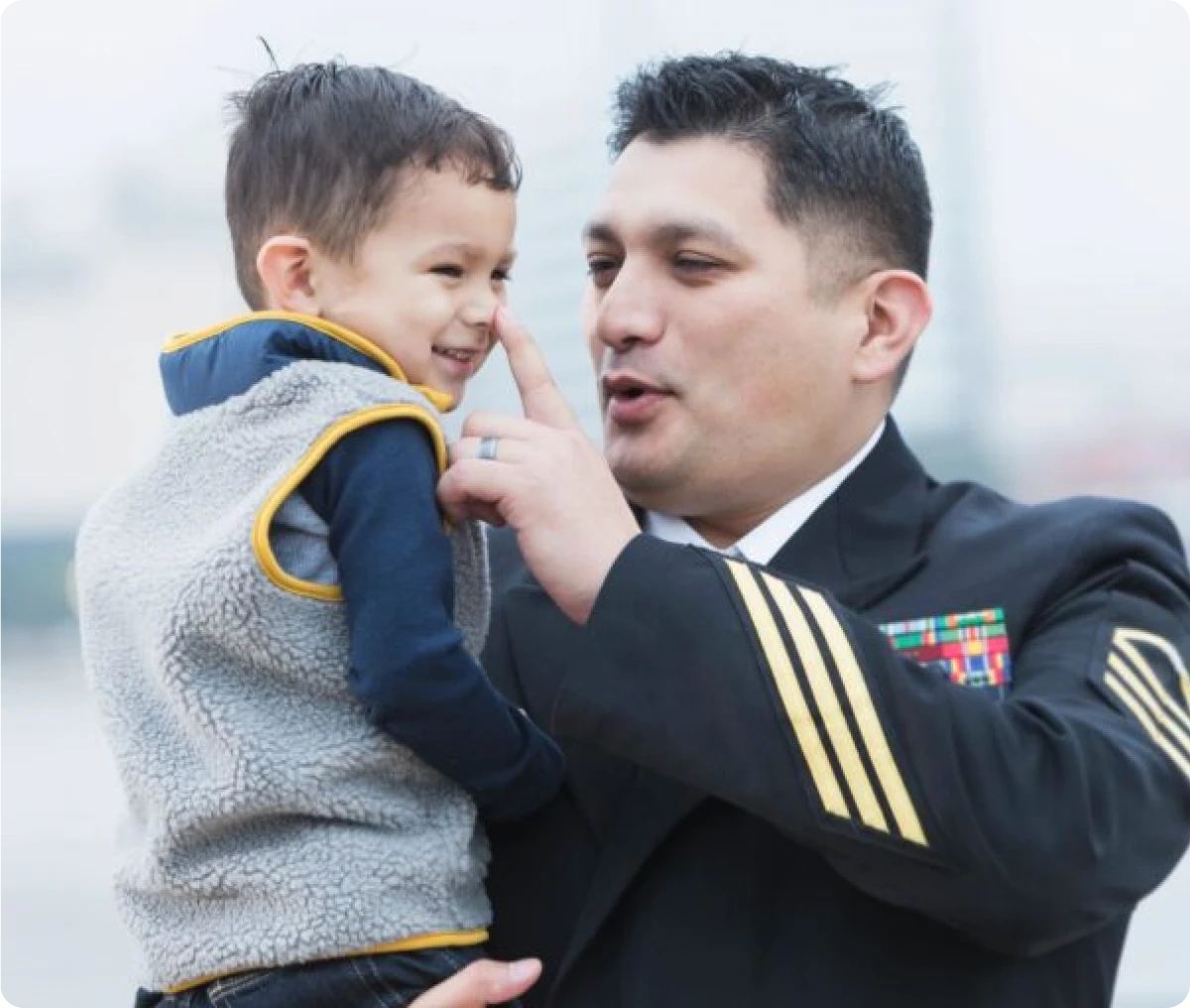 Man in uniform playfully touching child's nose.