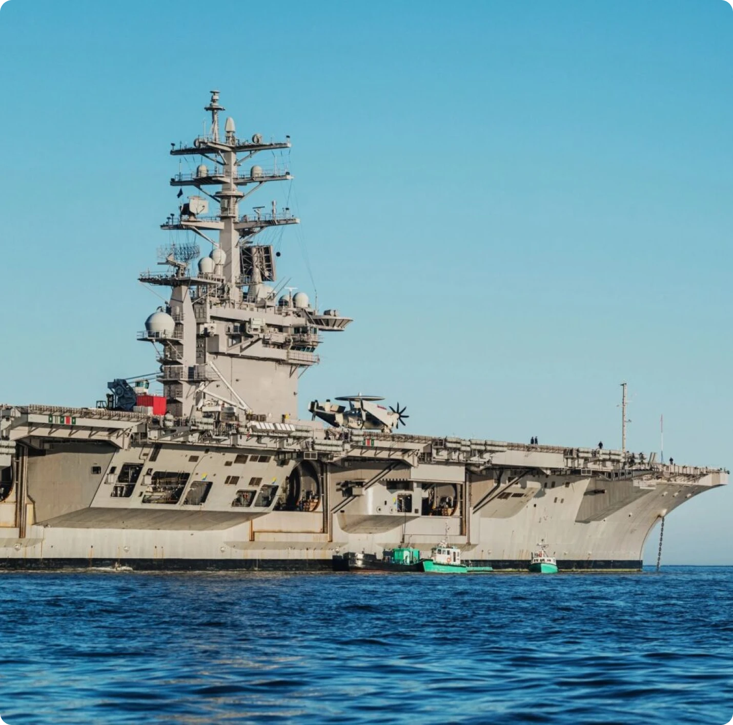 Aircraft carrier on open sea, clear sky.